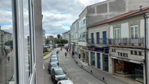 Vistas a una calle con coches y edificios aparcados en Lar ABEANCOS en Melide
