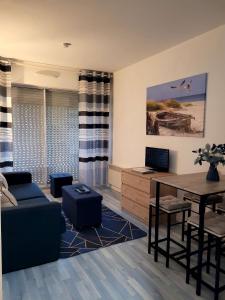 ein Wohnzimmer mit einem blauen Sofa und einem Tisch in der Unterkunft Les Portes de la Mer in Villers-sur-Mer