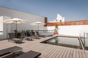 un patio con piscina, sillas y sombrillas en BYPILLOW La Sal, en Cádiz