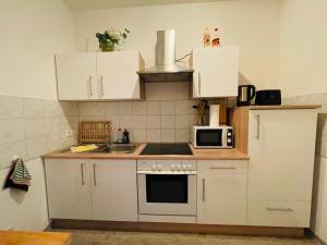 - une petite cuisine avec des placards blancs et un four micro-ondes dans l'établissement Ferienwohnung Zentrum/Hauptbahnhof, à Leipzig