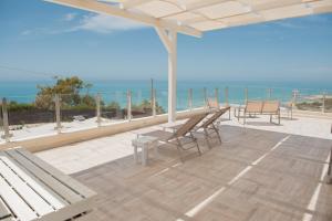 a patio with benches and a view of the ocean at Villa Quantum in Siculiana Marina