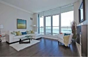 a living room with white furniture and large windows at Million Dollar Lake-view - Spacious 2 bedroom- 2 bathroom Condo across the lake with stunning lake view in Toronto