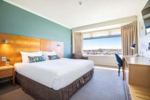 um quarto de hotel com uma cama grande e uma janela em Gateway Hotel by Nightcap Plus em Devonport