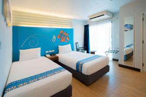 a hotel room with two beds and a blue wall at Days Inn by Wyndham Patong Beach Phuket - SHA Extra Plus in Patong Beach