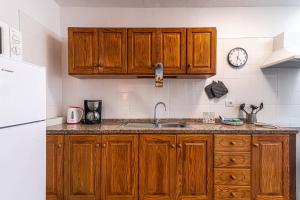 a kitchen with wooden cabinets and a sink and a clock at Acogedor apartamento en La Listada cercano a la Playa by Alterhome in La Listada