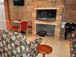 a living room with a brick fireplace with a couch at Great White Accommodation in Kleinbaai