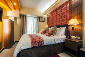 a bedroom with a large bed with a red headboard at Tivoli Garden Residences - Iris Tower in Manila +22 photos