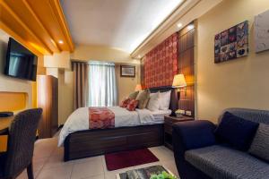 a hotel room with a bed and a desk and chairs at Tivoli Garden Residences - Iris Tower in Manila