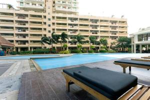 a bench in front of a swimming pool with a building at Tivoli Garden Residences - Iris Tower in Manila