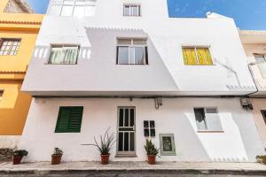 a white house with green shutters and potted plants at Acogedor apartamento en La Listada cercano a la Playa by Alterhome in La Listada