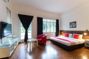 um quarto com uma cama, uma televisão e uma cadeira vermelha em OYO 161 Lodge Paradize Hotel em Kuala Lumpur