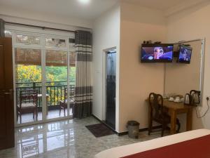 a room with a television on a wall with a table and a balcony at Jenushi homestay in Kandy