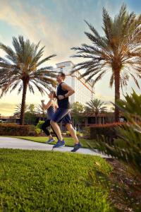two people running down a sidewalk with palm trees at DoubleTree by Hilton Hotel Orlando at SeaWorld in Orlando