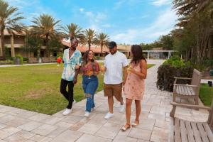 Un groupe de trois personnes parcourant une cour dans l'établissement DoubleTree by Hilton Hotel Orlando at SeaWorld, à Orlando