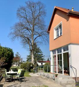 une maison avec une table, des chaises et un arbre dans l'établissement Ferienwohnung am Kronhof, à Lychen