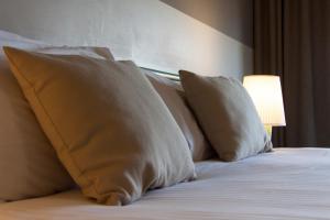 a bed with four pillows and a lamp on it at Hotel Berta in Desenzano del Garda