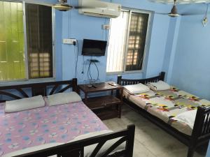 two beds in a room with blue walls and windows at Centerpoint Guest House in Kolkata