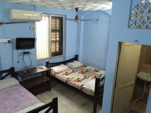 a bedroom with two beds and a table and a tv at Centerpoint Guest House in Kolkata