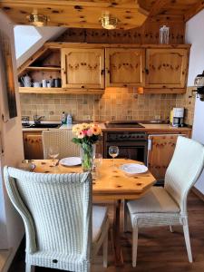 una cocina con una mesa de madera con sillas y flores. en Winterberg Appartement 21077, en Winterberg