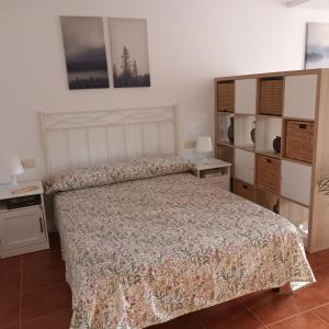 a bedroom with a bed with a bedspread and shelves at Apartamento Bambadela in Cala del Moral