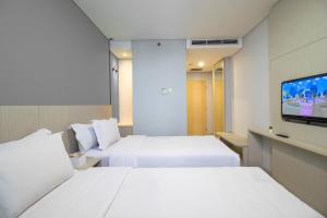 a hotel room with two beds and a flat screen tv at MIC Residence in Kejayan