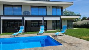 two chairs and a swimming pool in front of a house at Luxury Apartments in Balatonalmádi, Almádi Lux Apartman I - Ocean Blue in Balatonalmádi