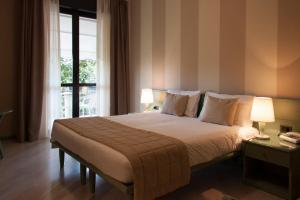una camera da letto con un letto con due lampade e una finestra di Hotel Berta a Desenzano del Garda