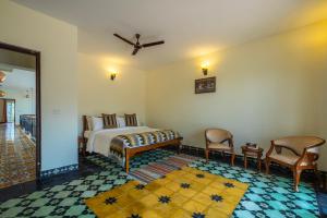 ama Stays & Trails Anjanagiri , Kotagiri في كوتاغيري: غرفة نوم بسرير وكرسيين في غرفة +5 صور