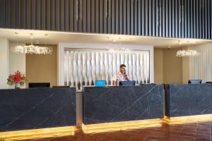 a woman standing behind a counter with a laptop at DoubleTree by Hilton Damai Laut in Lumut