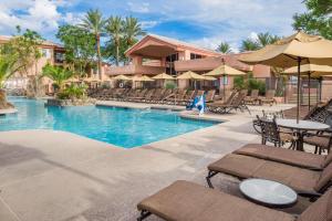 a resort pool with chairs and tables and umbrellas at Hilton Vacation Club Scottsdale Villa Mirage in Scottsdale