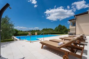 a pool with chaise lounge chairs next to a house at VILLA BEYBE with Jacuzzi, large private pool 50m2, BBQ,free WIFI, 3 bedrooms in Gata