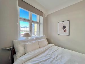 a white bed in a bedroom with a window at Stylish flat next to metro in Helsinki