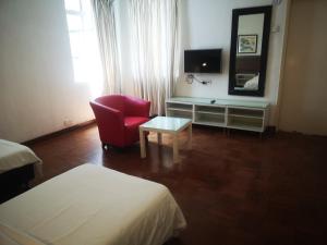 um quarto de hotel com uma cadeira vermelha e um espelho em OYO 161 Lodge Paradize Hotel em Kuala Lumpur
