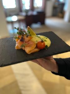 a person holding a piece of food on a black plate at Golfhotel Bodensee in Weißensberg