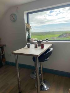 a table with two cups on it in front of a window at Island View Apartment in Miltown Malbay