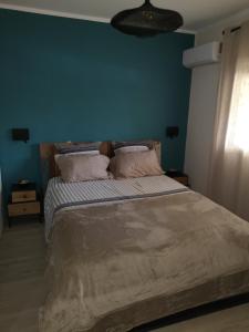 a bedroom with a large bed with a blue wall at Moana Beach Apartment in Noumea
