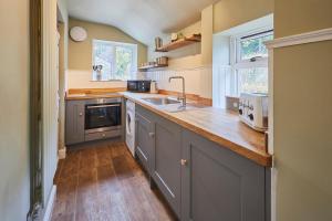 a kitchen with gray cabinets and a wooden floor at Host & Stay - The Old Post Office in Chatton