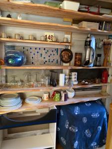 a shelf filled with dishes and other items in a kitchen at Soustons plage Maison terrasse 2 pers et 1 enfant Les villas du lac Tennis mini golf in Soustons