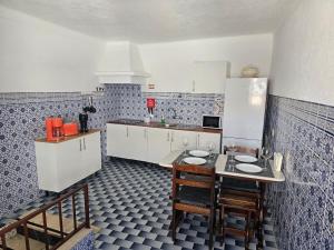 a kitchen with white cabinets and a table and chairs at A Casa D'eles in Póvoa e Meadas