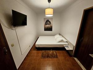 a small room with a bed and a tv at A Casa D'eles in Póvoa e Meadas