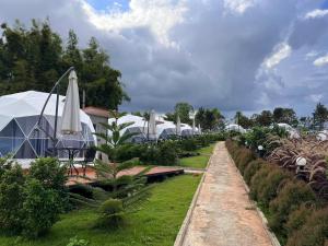 a garden with umbrellas and a row of tents at See Scape Camping Khaokho in Ban Nong Bong