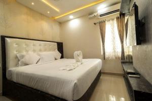 a bedroom with a bed with white sheets and a window at SR BOUTIQUE STAY SERVICE APARTMENT in Coimbatore