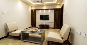 a living room with a table and chairs and a tv at SR BOUTIQUE STAY SERVICE APARTMENT in Coimbatore