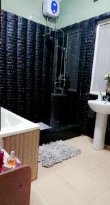 a bathroom with a shower and a tub and a sink at Lajungle Muyenga in Kampala