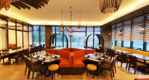 um restaurante com um sofá laranja e mesas e cadeiras em The Aurora Subic Hotel Managed By HII em Olongapo