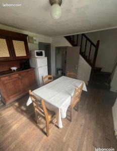 une cuisine avec une table et des chaises blanches ainsi qu'un escalier dans l'établissement maison de campagne, à Saint-Martin-Château