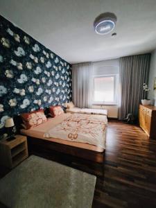 1 dormitorio con 1 cama grande y pared de flores en Alteschule15, en Leibsch