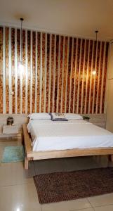 1 dormitorio con 1 cama y pared de madera en Lajungle Muyenga, en Kampala