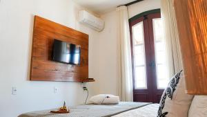 a bedroom with a bed and a tv on the wall at Pouso da Rita - Tiradentes in Tiradentes