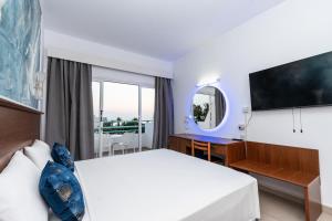 Habitación de hotel con cama, escritorio y espejo. en Adelais Bay Hotel en Protaras